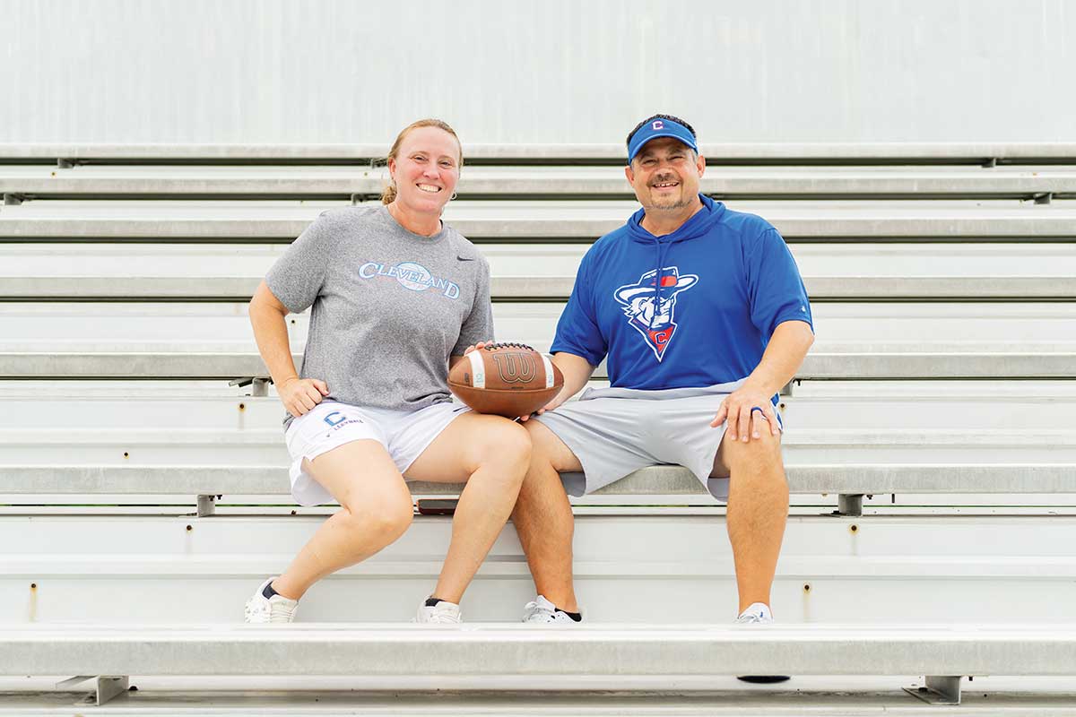 coaches sitting on bleachers holding a football