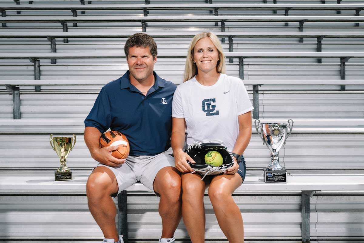 couple sitting on bleachers with various sports equipment