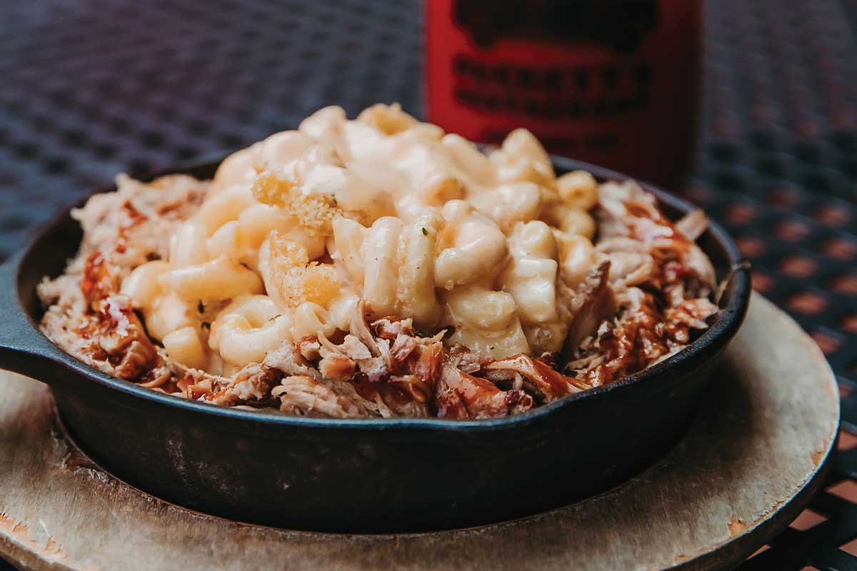 mac and cheese on top of pulled pork in iron skillet