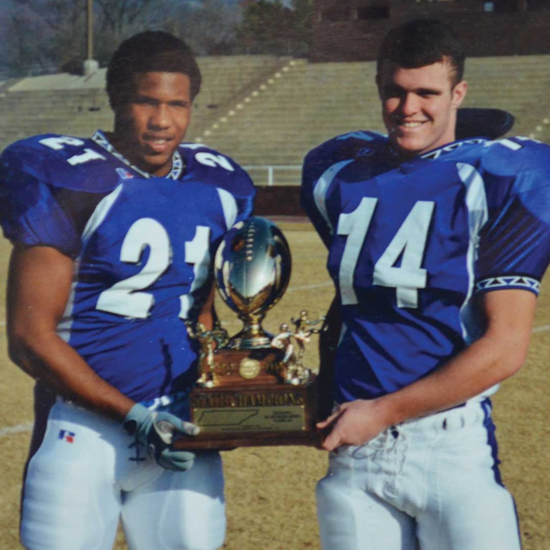 Two football players smiling with trophy